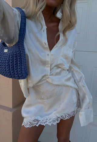 front-view-of-dubois-bias-mini-skirt-in-pearl-with-lace-hem-trim-styled-with-matching-jacquard-shirt-and-blue-woven-bag