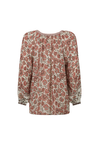 A woman modeling a long-sleeve bohemian-style blouse with a rust-brown and cream floral pattern