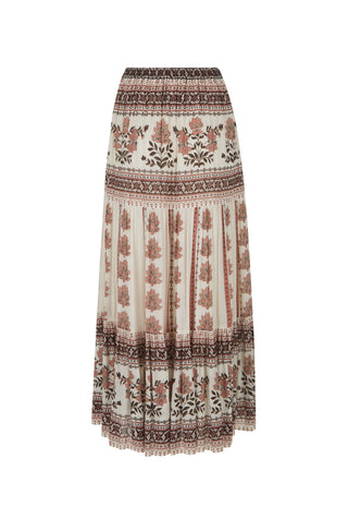 A woman modeling a bohemian-style two-piece outfit featuring a white sleeveless lace-trimmed top and a long cream maxi skirt with brown floral and geometric patterns
