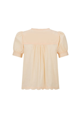 a-light-peach-colored-blouse-with-short-puff-sleeves-a-gathered-smocked-bodice-and-a-scalloped-hem-shown-against-a-plain-white-background