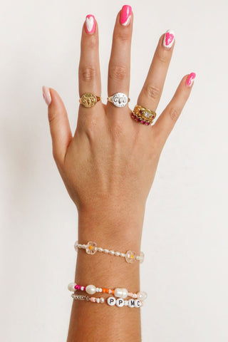 close-up-image-of-a-hand-with-painted-nails-wearing-playful-beaded-bracelets-and-rings-including-that-of-the-spell-s-silver-stargazer-zodiac-ring